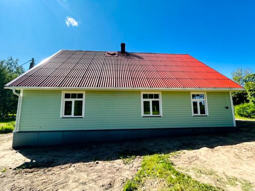 Ühekorruseline heleroheline maja punase viilkatusega ja valgete akendega.